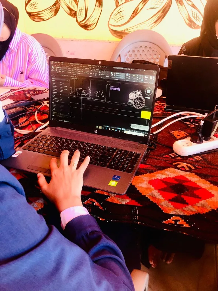 An engineering student working on a CAD drawing on a laptop