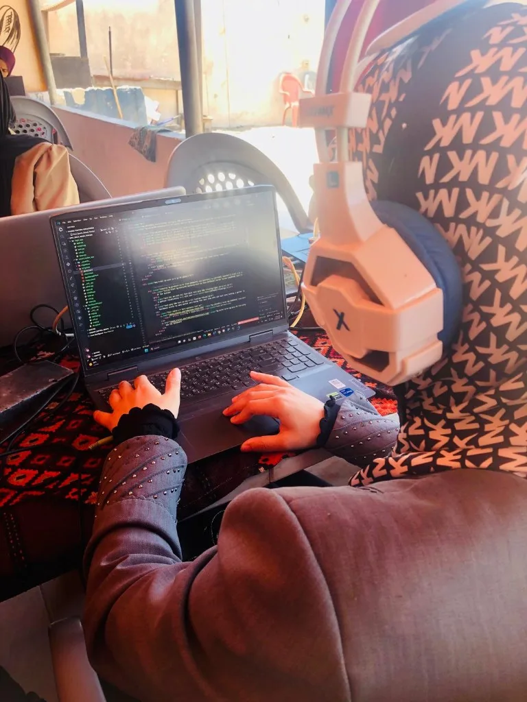 A student writing code in a development environment, headset resting beside the laptop