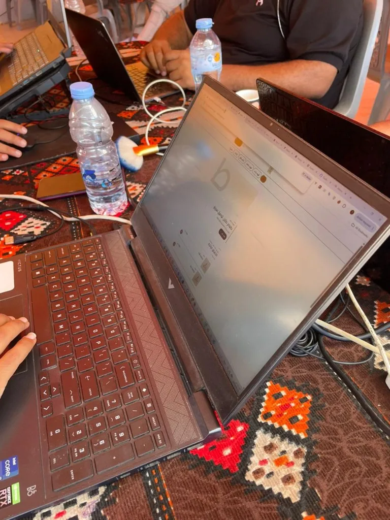 Laptops, cables and a shared power strip on a patterned table covering