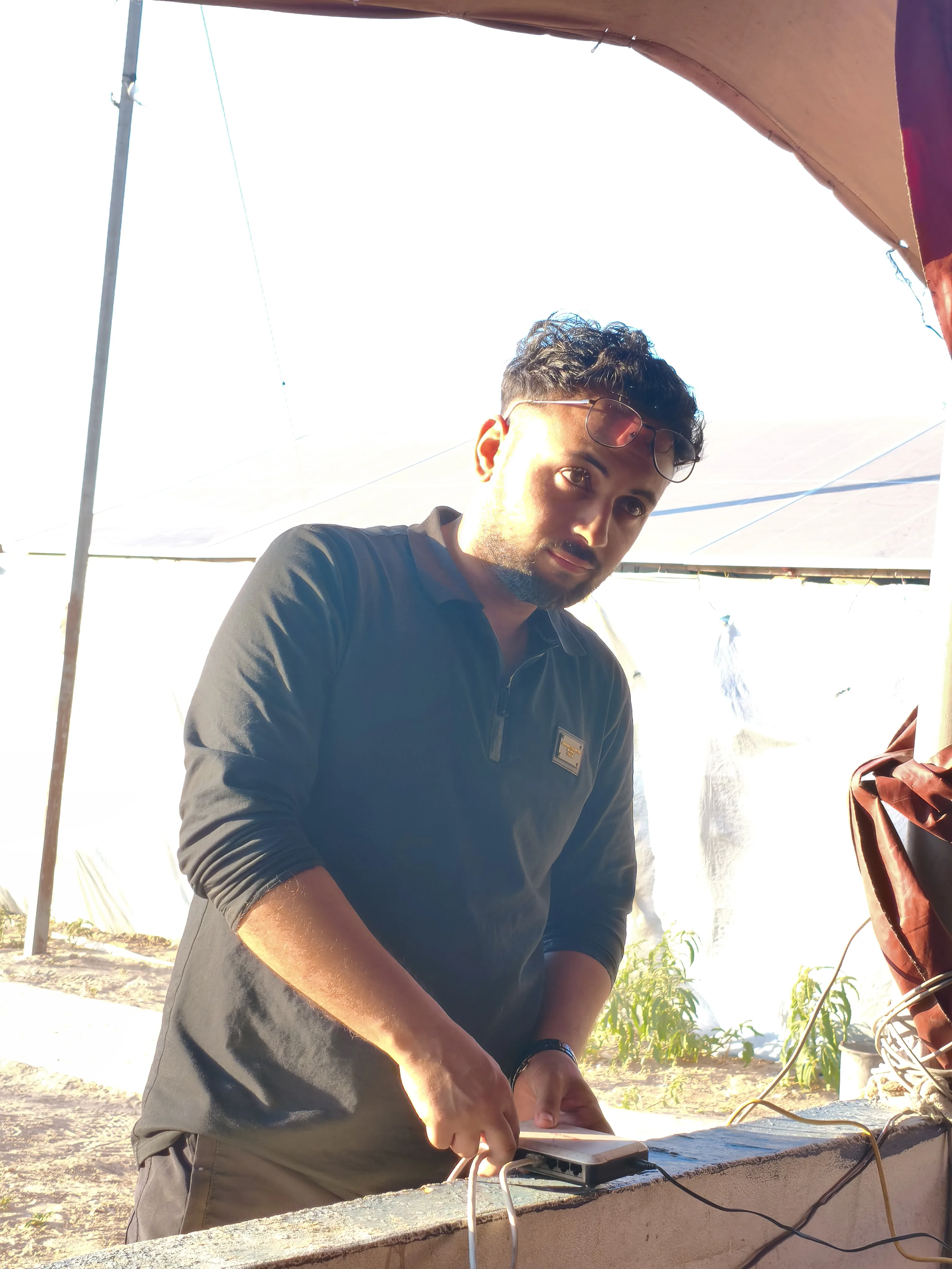 A Riva Hub team member connecting a network switch on an outdoor wall beside the solar array