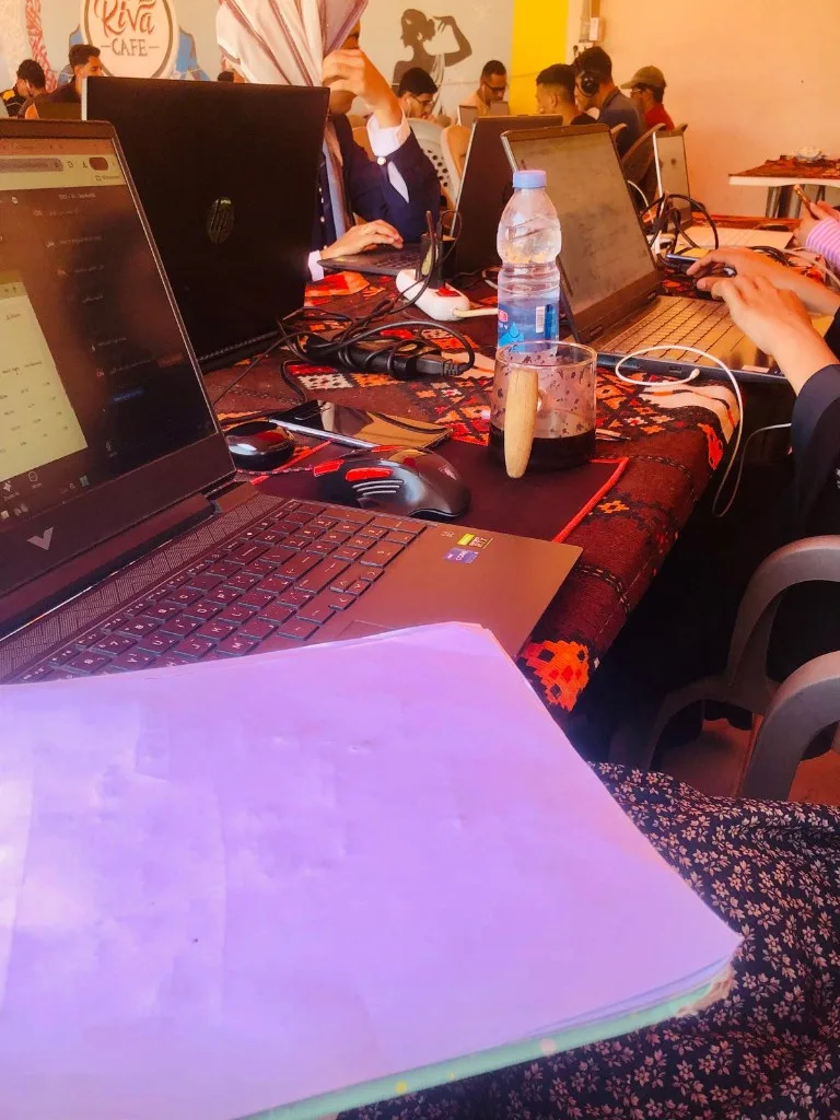 Students seated along shared tables, laptops connected to power strips running down the centre